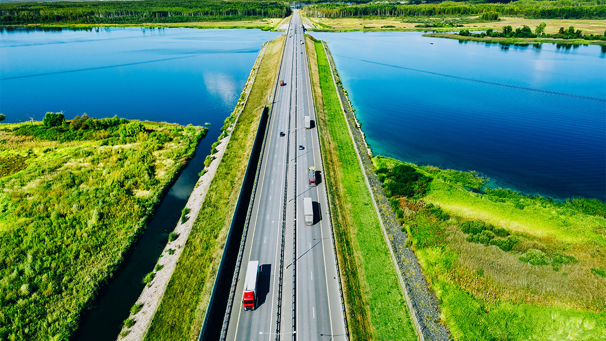 Imagem aérea de estrada com movimento tranquilo cortando rio
