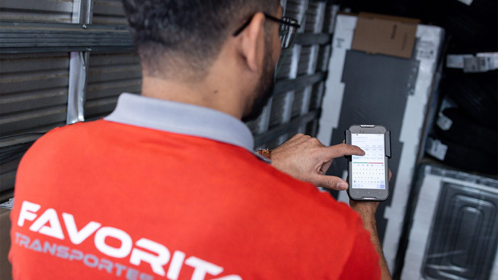 Funcionário da Favorita mostrando app de rastreamento de cargas