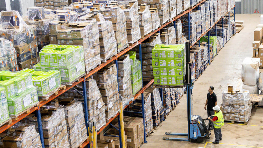 Funcionários trabalhando em galpão da Favorita Transportes organizando mercadorias com máquinas