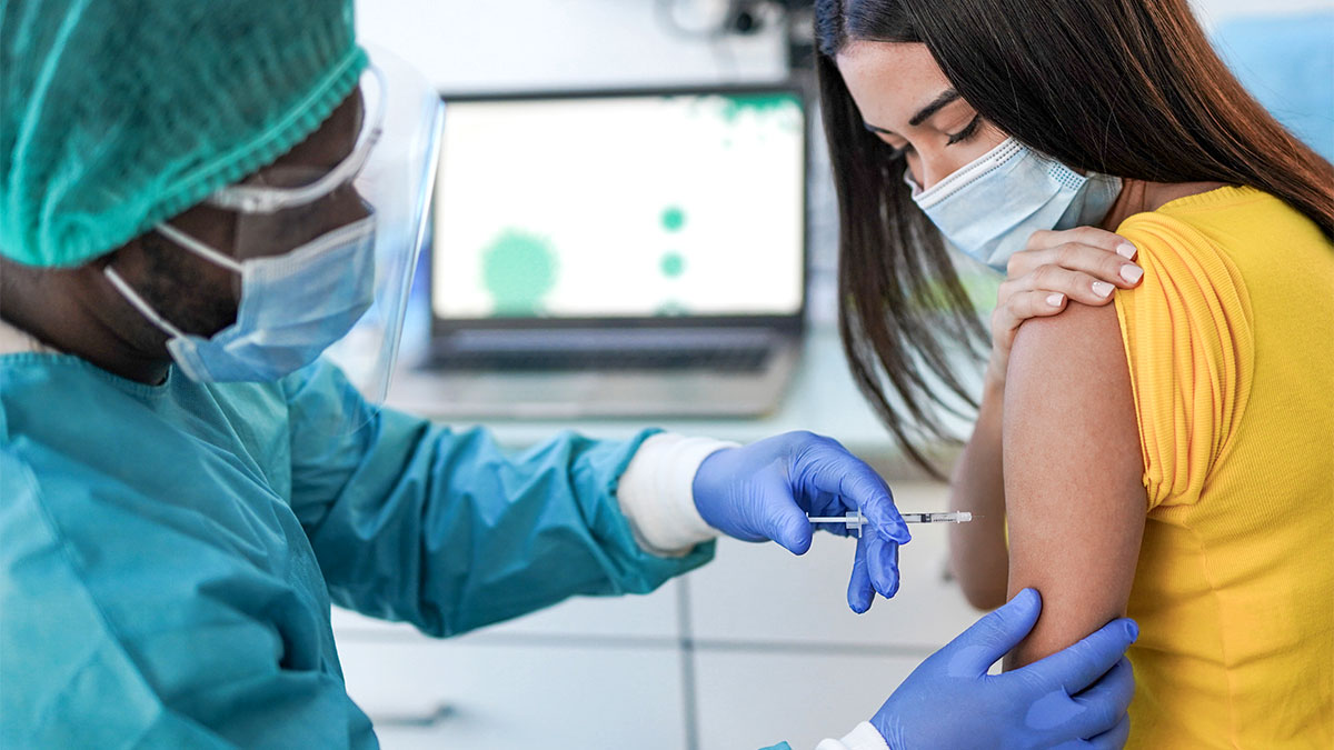 Profissional de saúde aplicando vacina em campanha de prevenção contra hepatites durante o Julho Amarelo.