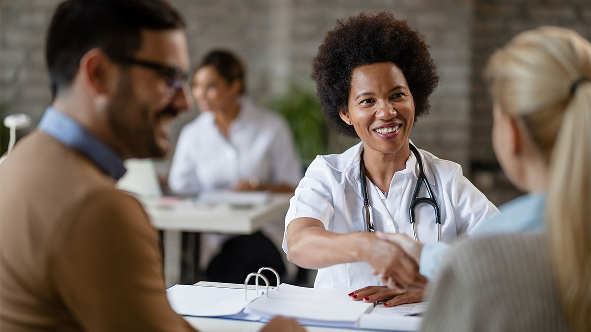 Profissional da saúde cumprimenta colaboradores em ambiente corporativo, simbolizando a integração entre cuidados médicos, bem-estar e promoção da saúde no ambiente de trabalho.