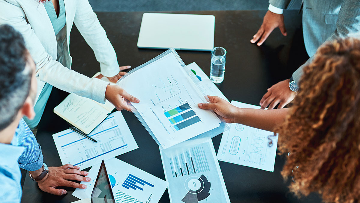 Reunião empresarial analisando gráficos e relatórios para desenvolver estratégia logística eficiente e reduzir custos operacionais.