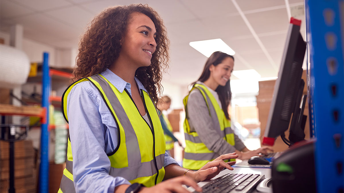 Colaboradoras de operador logístico utilizando computadores no centro de distribuição, representando como o MDFe e EDI trazem eficiência e segurança na logística.