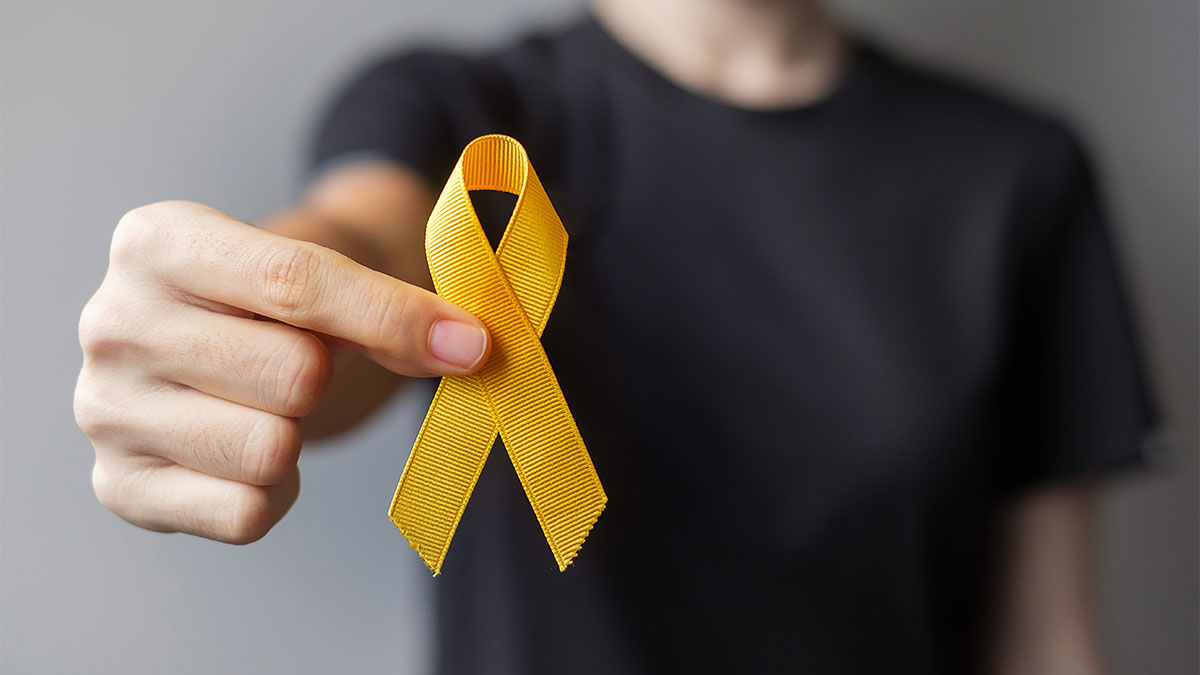 Mão segurando laço amarelo, símbolo da campanha Setembro Amarelo de prevenção do suicídio e valorização da vida.