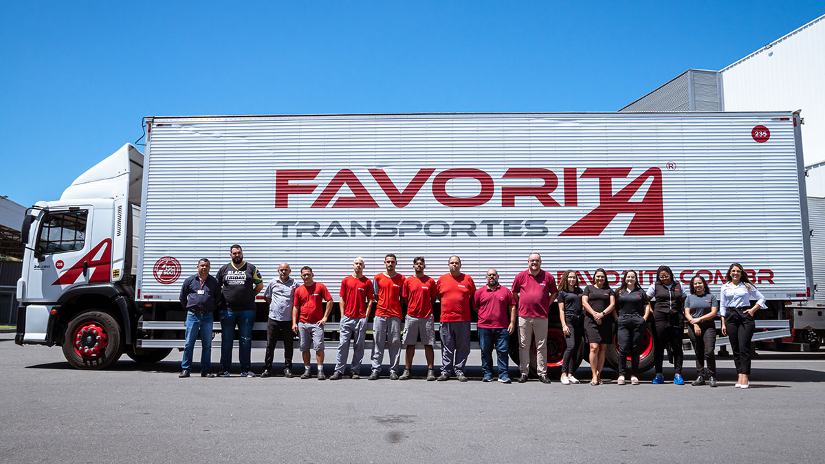 Equipe da Favorita Transportes em frente a um caminhão da empresa, simbolizando o protagonismo social e o compromisso com o desenvolvimento humano e coletivo.