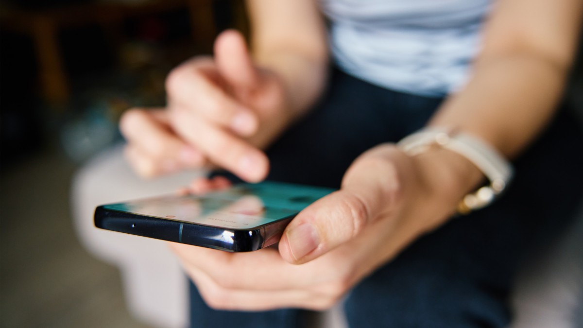 Pessoa usando um smartphone para acessar os canais oficiais da Favorita, representando comunicação direta, segura e confiável.